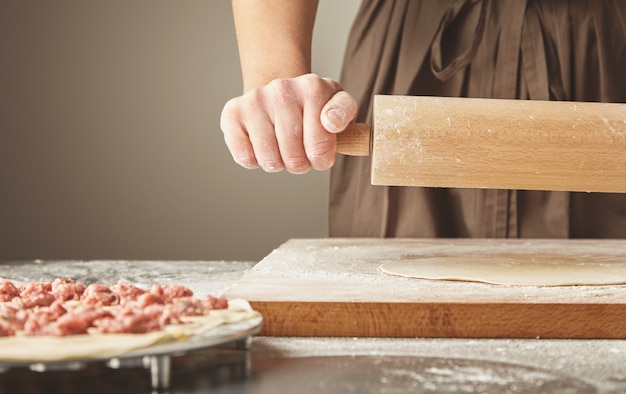 Processo passo a passo de fazer bolinhos caseiros, ravióli ou pelmeni com recheio de carne picada usando molde de ravióli ou ravioli maker. Isolado no lado direito. Achate a massa com um rolo de massa