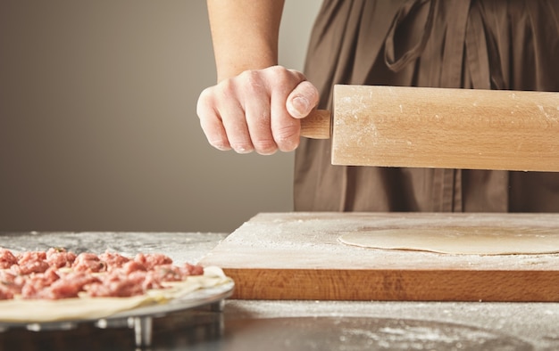 Processo passo a passo de fazer bolinhos caseiros, ravióli ou pelmeni com recheio de carne picada usando molde de ravióli ou ravioli maker. isolado no lado direito. achate a massa com um rolo de massa