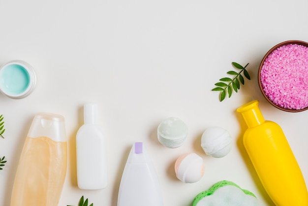 Produtos cosméticos com bomba de banho; sal rosa e creme em pano de fundo branco