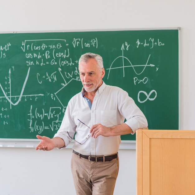 Professor cessante de pé no pódio e explicando o material