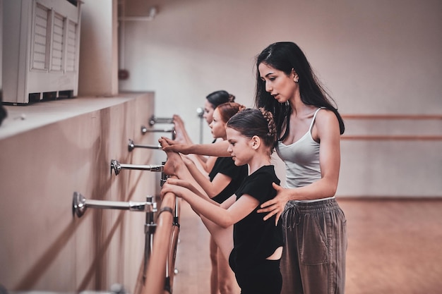 Foto grátis professor de balé experiente está mostrando a jovens bailarinas como fazer exercícios importantes e corrigi-los.