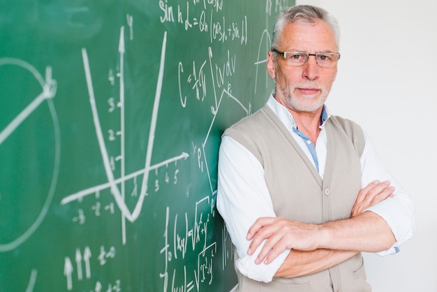 Professor de matemática envelhecido concentrado apoiando-se na lousa