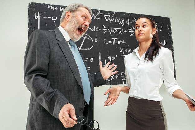 Professor do sexo masculino e jovem mulher contra lousa em sala de aula