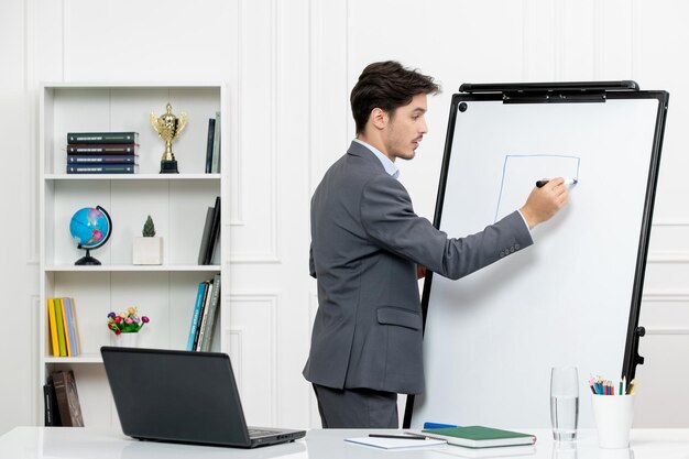 Professor instrutor inteligente em terno cinza em sala de aula com computador e quadro branco desenho quadrado