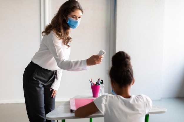 Professor medindo a temperatura de um aluno na aula