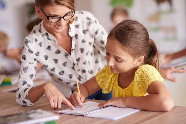 Foto grátis professora alegre ajudando seu aluno