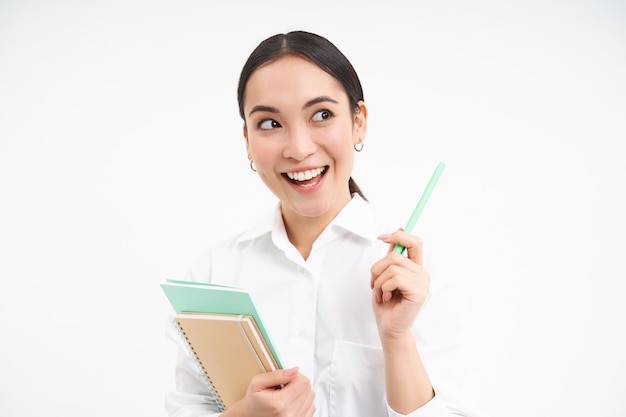 Professora asiática com notebooks sorrindo e parecendo confiante isolado no fundo branco