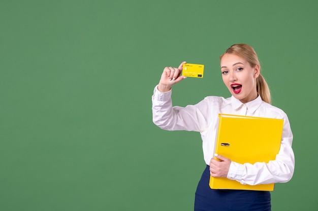 Professora de frente segurando arquivos amarelos e cartão do banco no verde