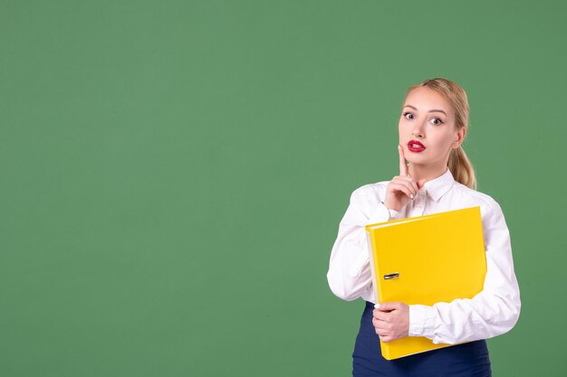 Professora de frente segurando arquivos amarelos em verde