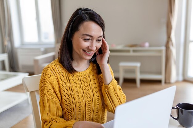 Professora de mulher de negócios asiática, tutora, usa fone de ouvido sem fio, videoconferência, chamando no laptop, conversa por webcam, aprendendo a ensinar no bate-papo on-line