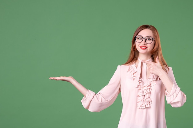 Professora de vista frontal em blusa rosa em fundo verde trabalho escola livro de cores jovem lição mulher estudante biblioteca faculdade trabalhos