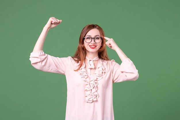 Professora de vista frontal em blusa rosa sobre fundo verde livro de trabalho de cor de faculdade estudante jovem lição escola trabalho mulher biblioteca