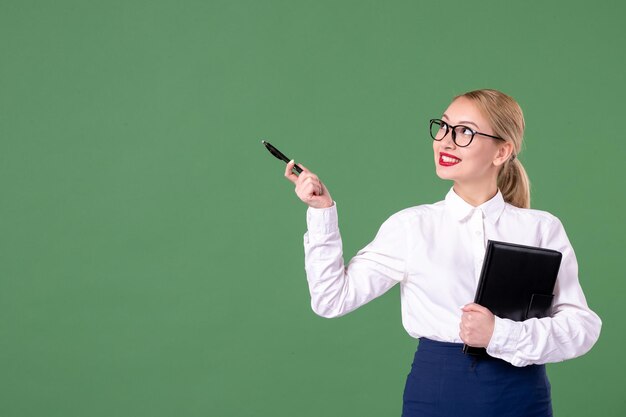 Professora de vista frontal em óculos de sol com bloco de notas e caneta em fundo verde livro de estudo escolar dinheiro trabalho uniforme estudante documento lição mulher