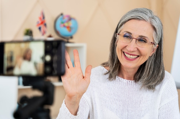 Professora sorridente de inglês fazendo aulas on-line em seu smartphone