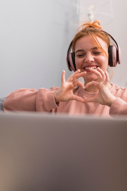 Professora sorridente mostrando sinal de coração para os alunos durante a aula online