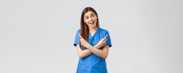 Profissionais de saúde evitam seguro de vírus e conceito de medicina Enfermeira sorridente entusiástica em uniforme azul apontando os dedos para o lado esquerdo e direito mostrando dois produtos ou banners