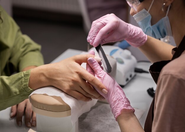 Profissional de nail art trabalhando em unhas de clientes