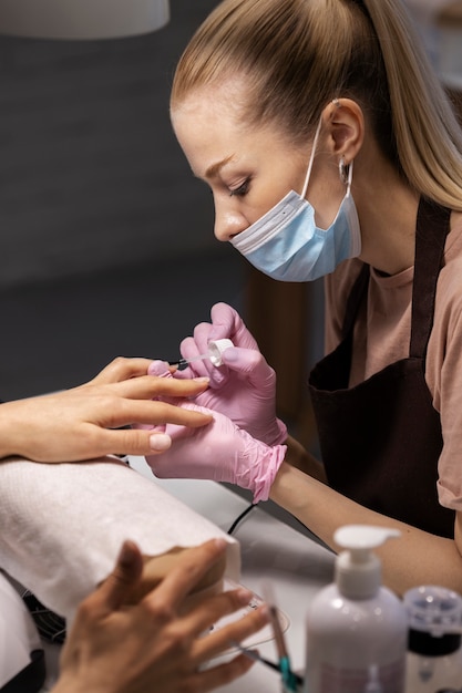 Profissional de nail art trabalhando em unhas de clientes