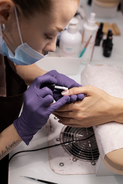 Profissional de nail art trabalhando em unhas de clientes