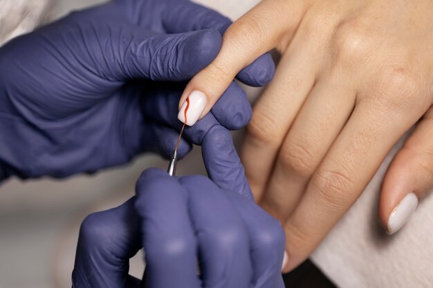 Profissional de nail art trabalhando em unhas de clientes