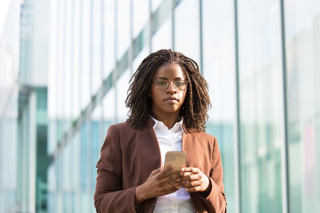 Profissional de negócios sério feminino segurando o smartphone