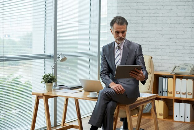 Profissional de negócios, trabalhando com tablet digital em seu escritório ecológico, sentado na mesa de madeira
