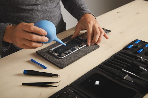 Profissional está trabalhando em seu laboratório para consertar e limpar a caixa do kit de ferramentas do smartphone com instrumentos específicos perto