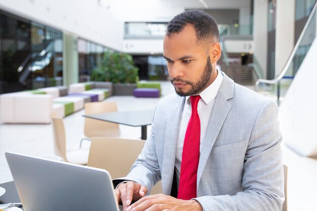 Profissional sério focado usando laptop e olhando para a tela