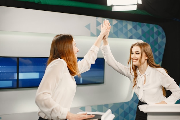 Programa televisivo de jogos com dois participantes nas tribunas. Mulheres empolgadas no estúdio de tv, filmando programa de tv.