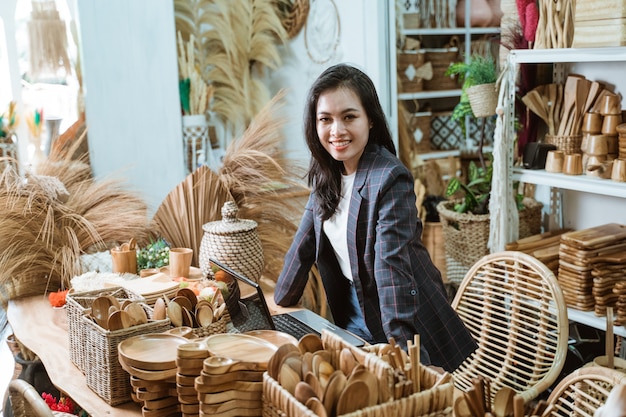 Proprietária de uma empresa asiática atraente em sua loja de arte e artesanato que vende produtos feitos de produtos naturais