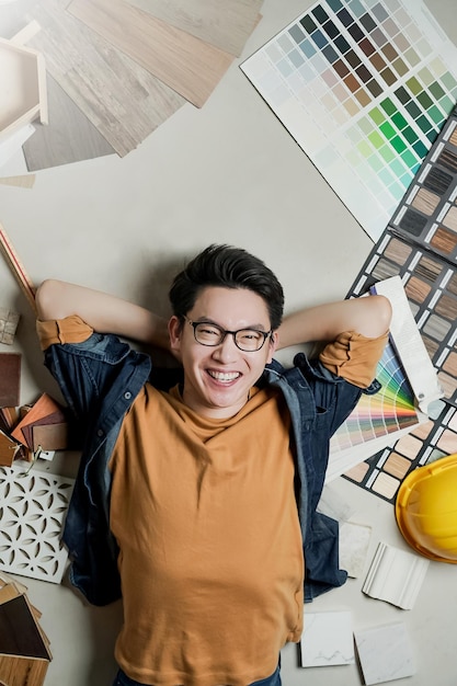 Proprietário de casa de homem asiático de felicidade inteligente deitado no chão com moldura de amostra de material de casa em torno do conceito de ideias de renovação de casa