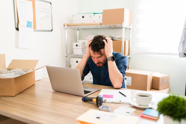 Proprietário de negócios hispânicos tendo problemas com sua empresa de inicialização. Empresário chateado se sentindo estressado e preocupado enquanto olha para a tela do laptop