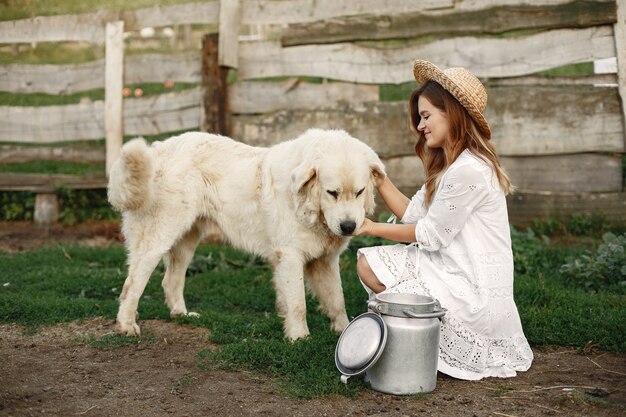 Proprietário e cão labrador retriever em um quintal. Mulher de vestido branco. Golden retriever.