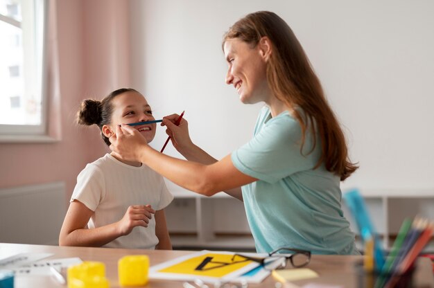 Psicólogo ajudando uma menina em terapia da fala em ambientes fechados