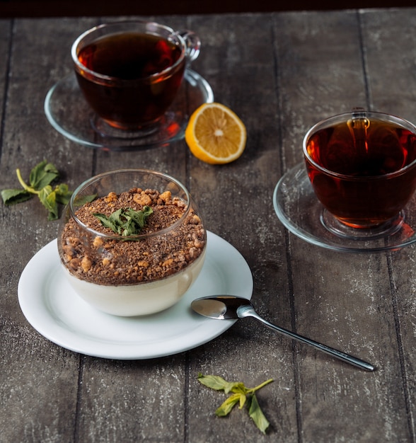 Pudim de baunilha coberto com migalhas de chocolate e nozes, servido com chá