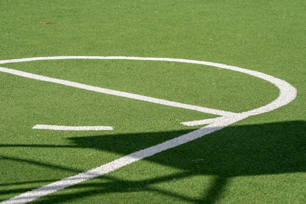 Quadra de basquete com gramado verde, grama artificial e linhas brancas