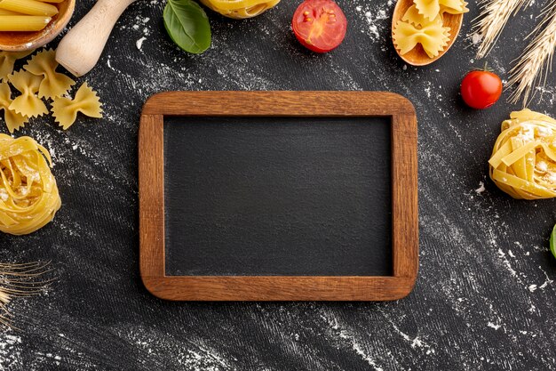 Quadro de arranjo de massas alimentícias não cozidas em fundo preto com moldura de madeira