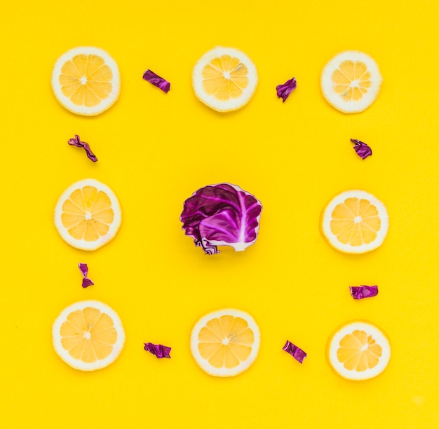 Foto grátis quadro de fatias de limão com repolho roxo no centro sobre fundo amarelo