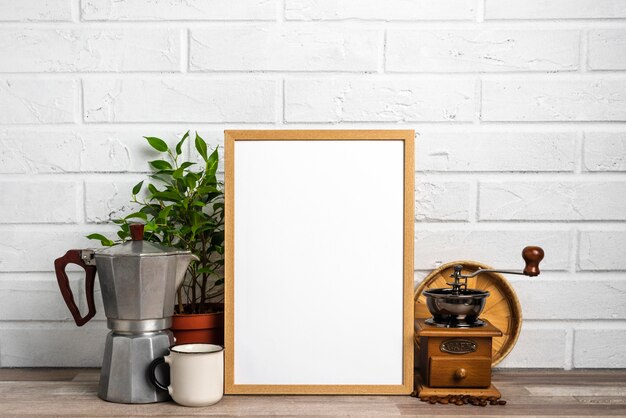 Quadro em branco ao lado do vaso de flores e moedor