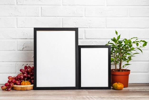 Quadro em branco ao lado do vaso de flores e uvas