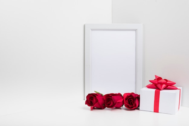 Quadro em branco com caixa de presente e rosas