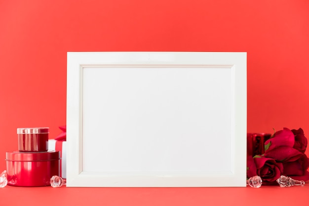 Quadro em branco com rosas vermelhas na mesa