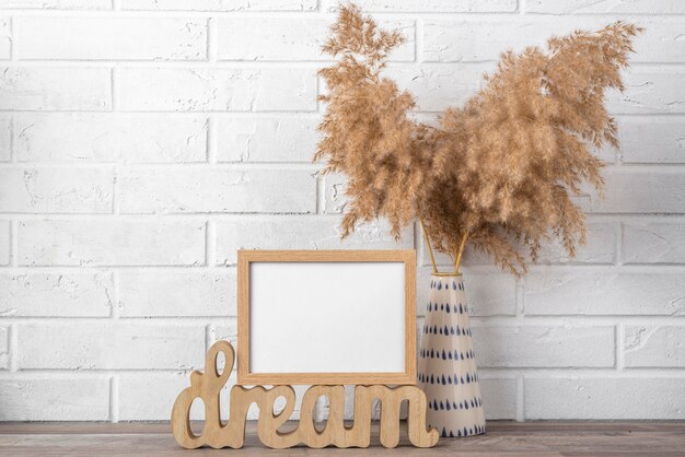 Quadro em branco na prateleira ao lado do vaso com folhas secas