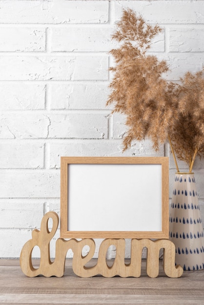 Quadro em branco na prateleira ao lado do vaso com folhas secas