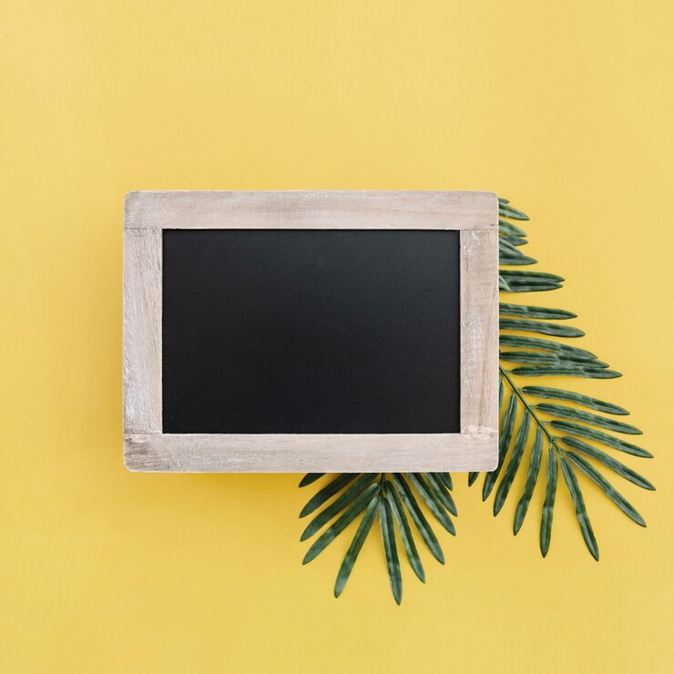Foto grátis quadro negro para mock up com folhas de palmeira sobre fundo amarelo