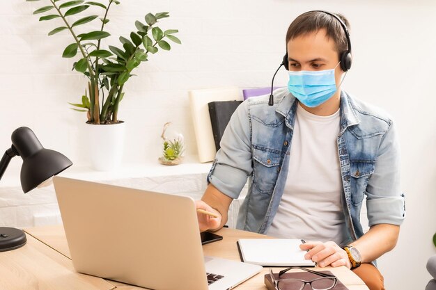 quarentena devido à pandemia de coronavírus. ficar em casa. homem de negócios trabalhando em casa, use uma máscara protetora. Trabalhe em casa com gel desinfetante. trabalho remoto, aprendendo devido à epidemia COVID-19.