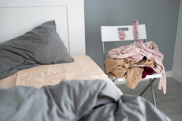 Quarto bagunçado de alto ângulo com roupas na cadeira