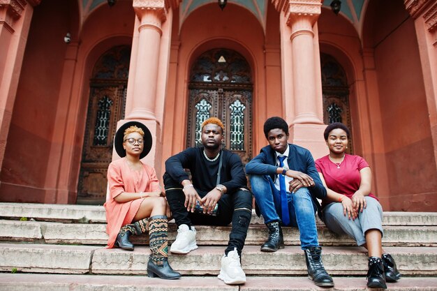 Quatro amigos africanos posaram ao ar livre contra a arquitetura antiga Duas garotas negras com caras