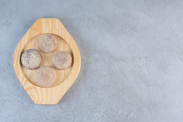 Quatro saborosas bolas de trufas colocadas em um prato de madeira.