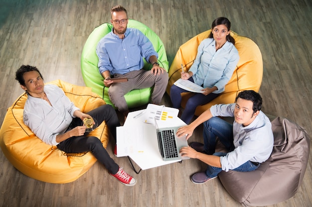 Foto grátis quatro trabalhadores e sentados em cadeiras beanbag
